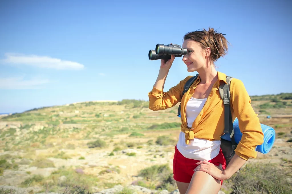 Photo of a healthy girl with a binocular in her hands doing birdwatching